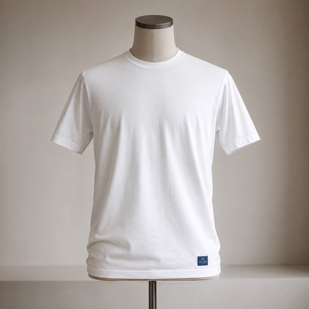 Minimalist white t-shirt on a neutral mannequin with subtle gradient background